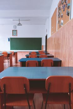 Estancia Infantil A tranquil empty classroom with wooden furniture and a green chalkboard, perfect for educational themes.