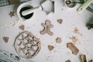 A top view of gingerbread cookies in various shapes with baking tools and ingredients.
